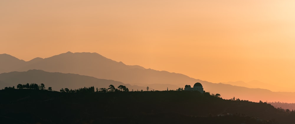 silhouette of trees and mountains during sunset