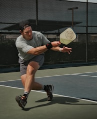 man in gray crew neck t-shirt and gray shorts sitting on basketball court