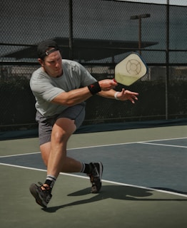 man in gray crew neck t-shirt and gray shorts playing pickleball