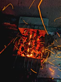 A vibrant shot of the outdoor Smokecraft stationary BBQ bar with meats cooking over glowing coals.