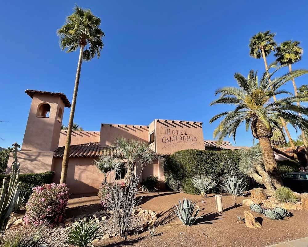 brown concrete building near palm trees under blue sky during daytime