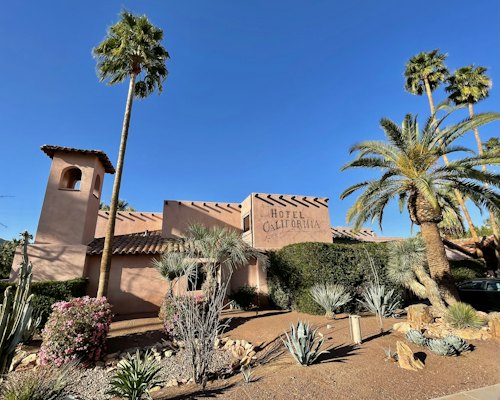 Brown concrete building near palm trees under blue sky during daytime