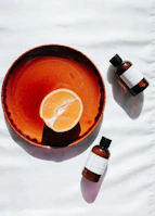 A hand holding a vibrant orange plate with subtle speckled glaze, sunlight casting soft shadows.
