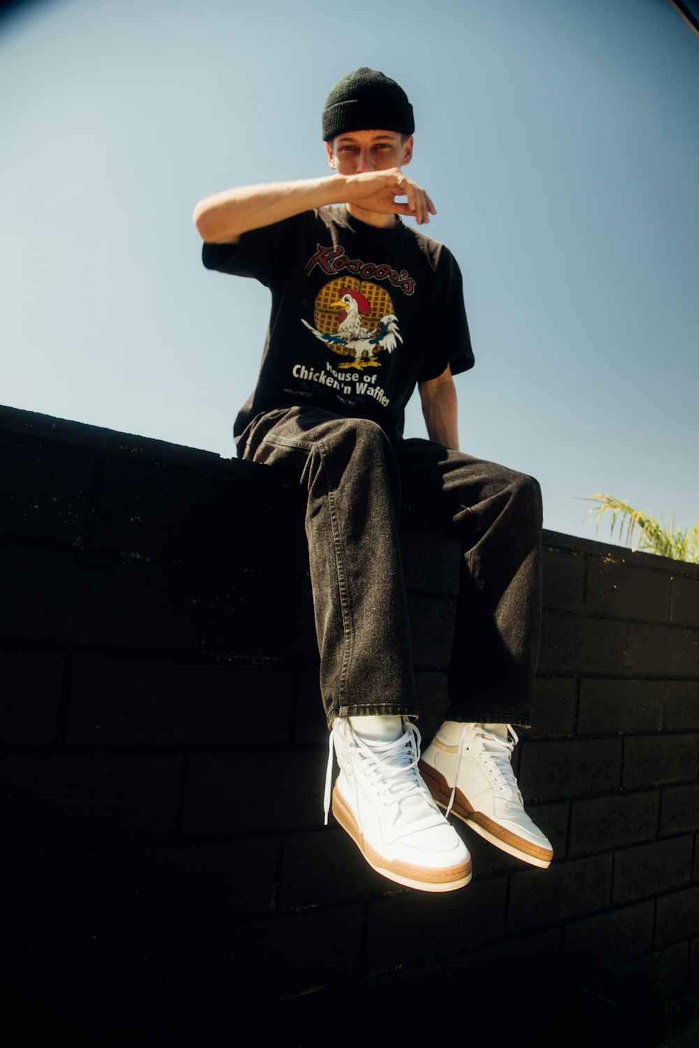 man in black t-shirt and black pants sitting on black concrete bench during daytime