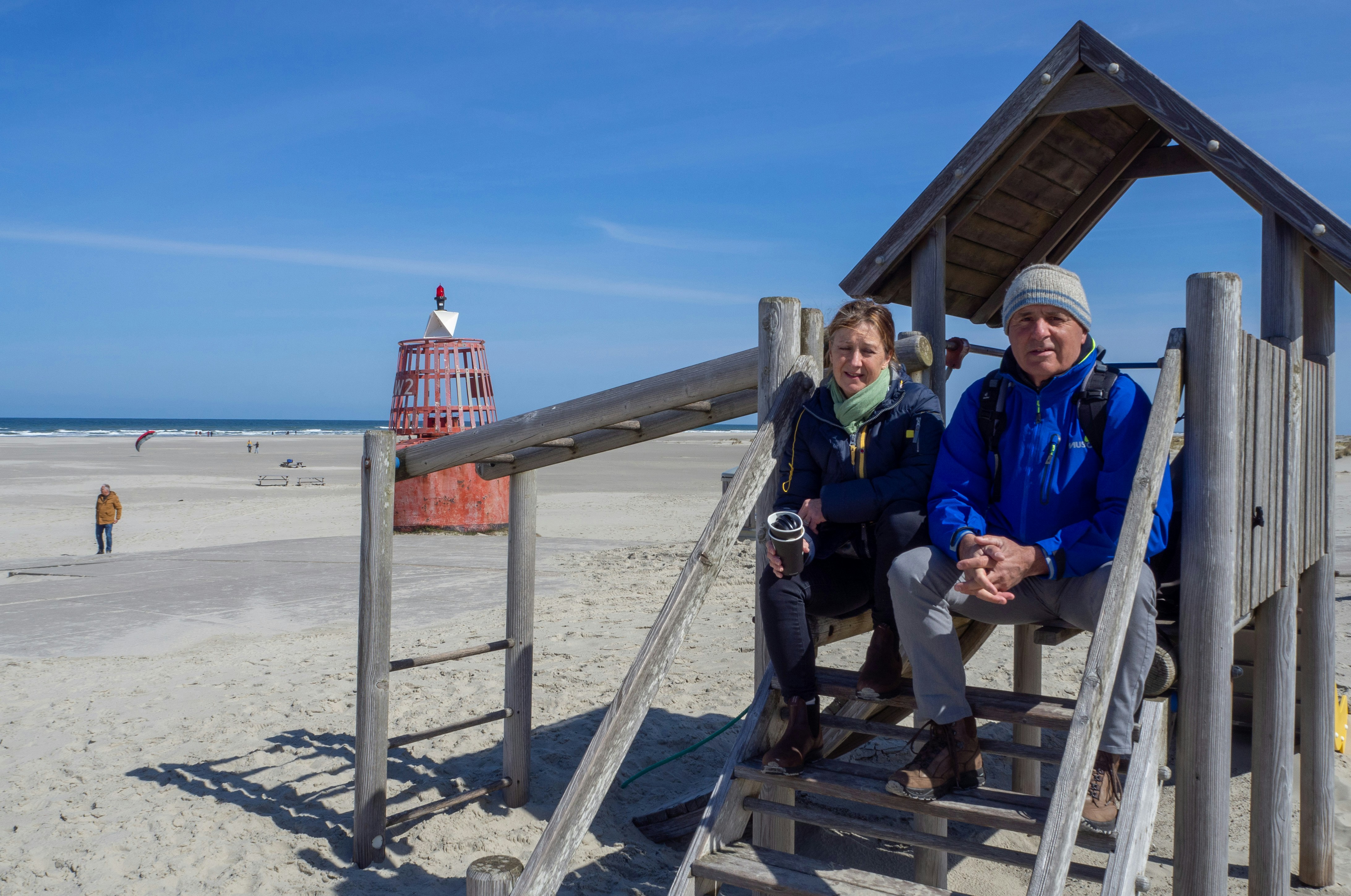 Man and woman standing on wooden dock near body of water during daytime