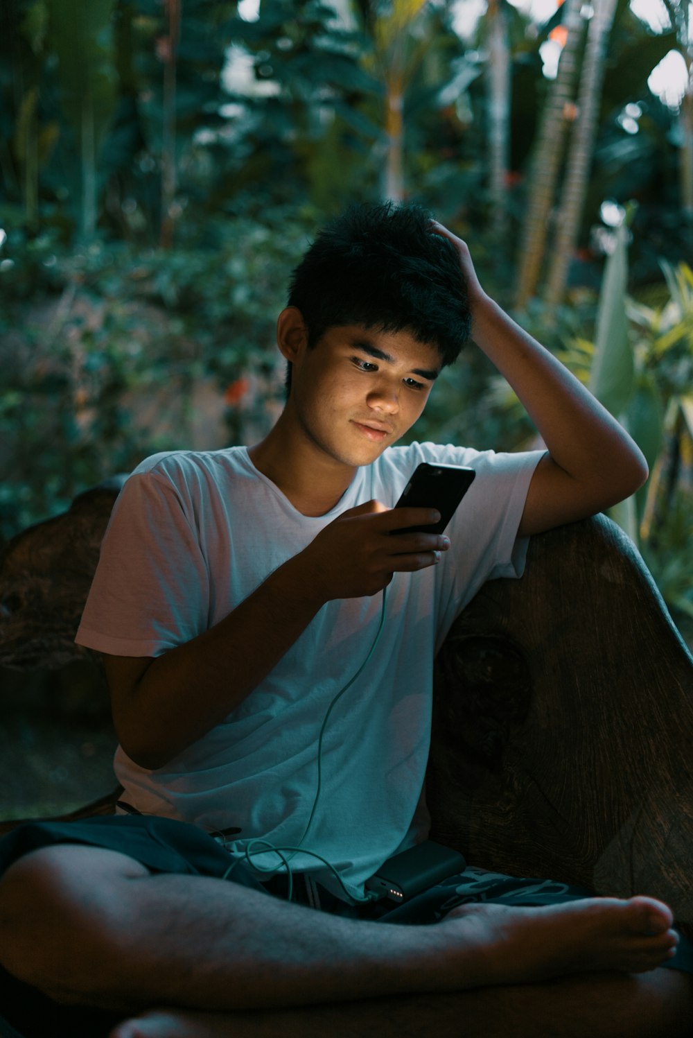 man in white crew neck t-shirt sitting on brown wooden bench