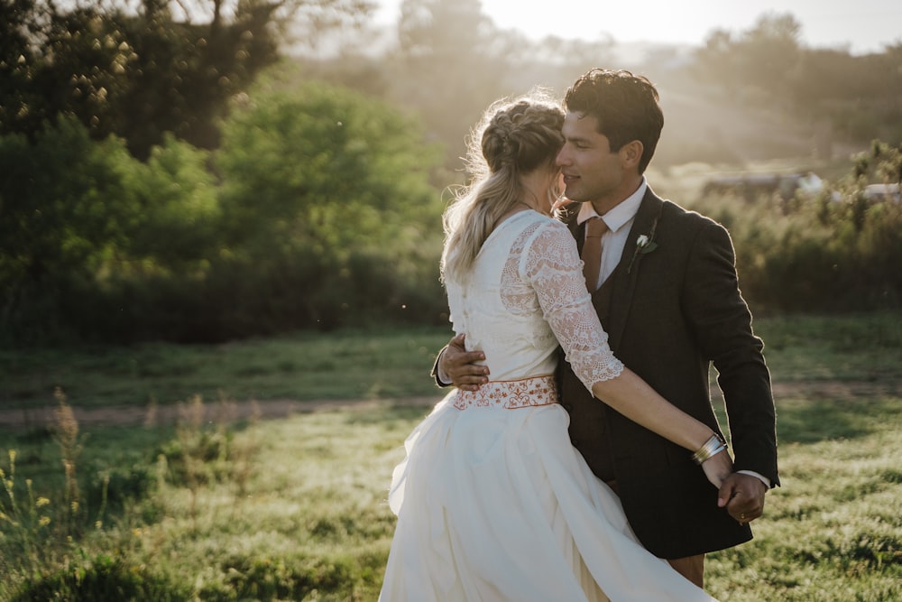 man in black suit holding woman in white dress