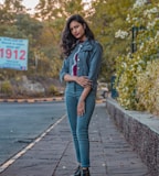 woman in gray hoodie and blue denim jeans standing on wooden dock during daytime