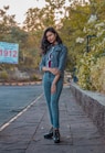 woman in gray hoodie and blue denim jeans standing on wooden dock during daytime