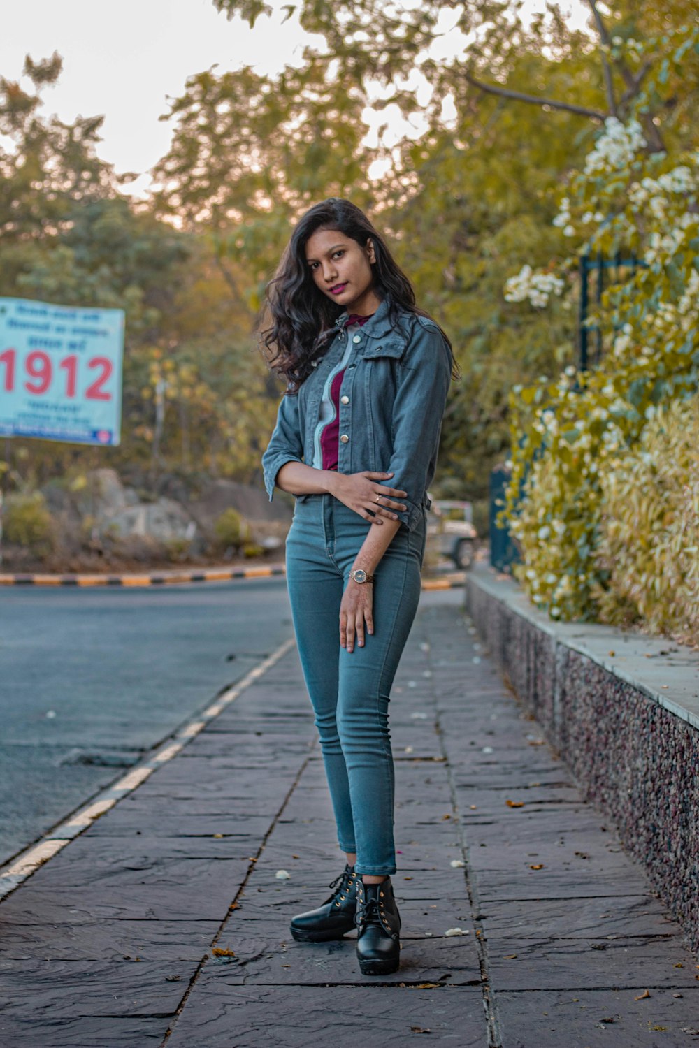 Donna in felpa con cappuccio grigia e jeans blu in piedi sul molo di legno durante il giorno