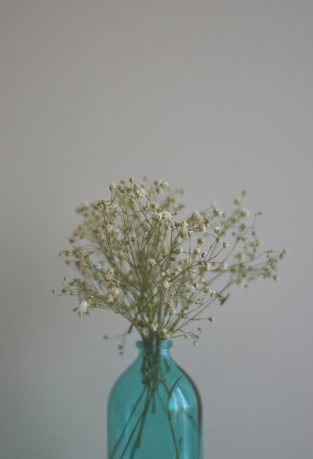 white flowers in blue glass vase