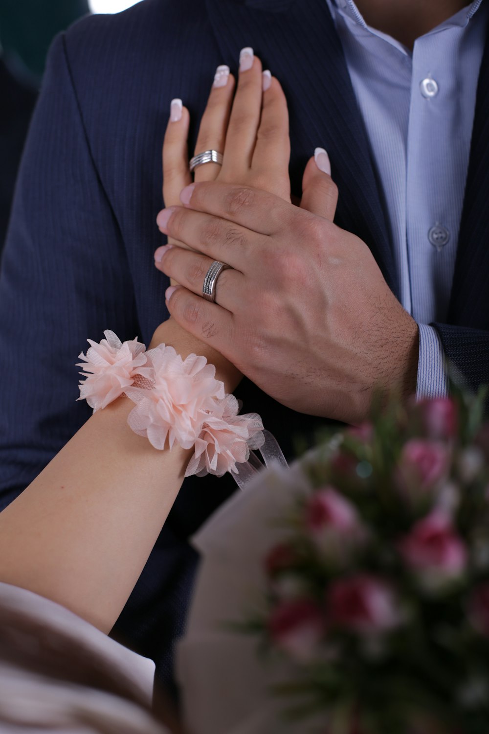 man in black suit jacket holding woman in white wedding dress