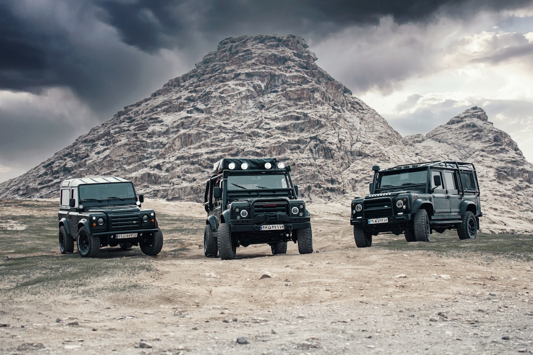 black jeep wrangler on brown field near brown mountain under white clouds during daytime