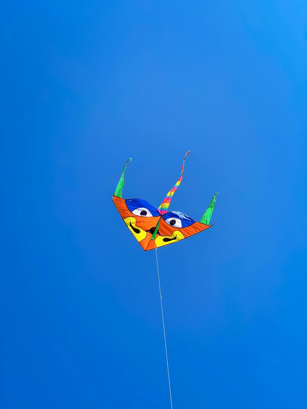 yellow and blue bird kite flying under blue sky during daytime