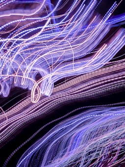 A dynamic display of colorful streaks and swirls of light against a dark background, creating an abstract and energetic visual effect.