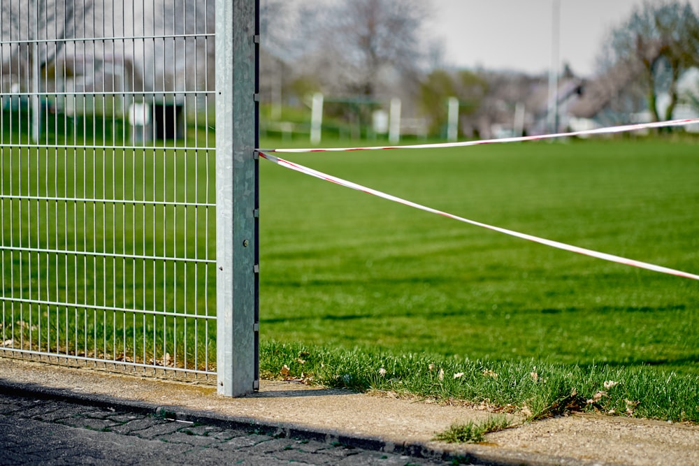 white metal fence on green grass field during daytime