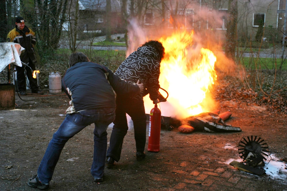 Hombre con chaqueta negra y jeans de mezclilla azul sosteniendo fuego naranja