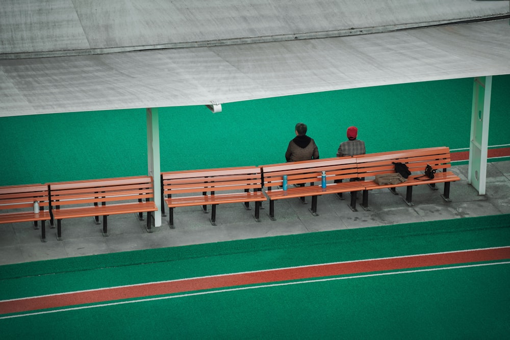 man in black t-shirt sitting on brown wooden bench