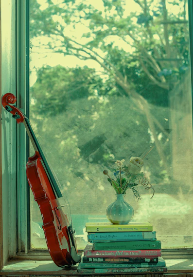 A cozy corner with a violin resting on a wooden chair beside colorful music books and soft natural light.