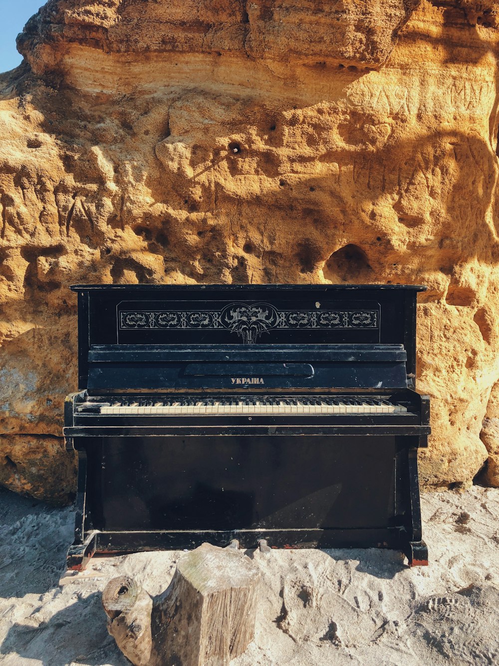black upright piano beside brown wall