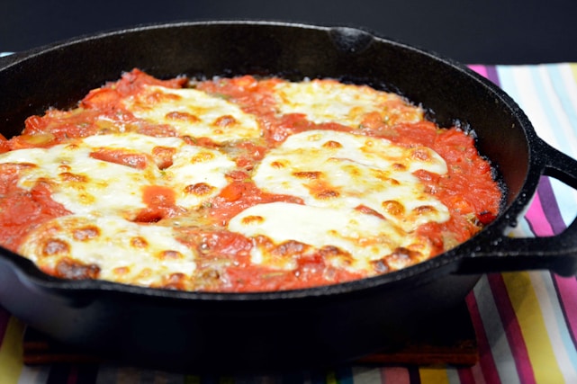 A vibrant plate of cheesy fusion dishes with melted cheese stretching invitingly under warm yellow lighting.