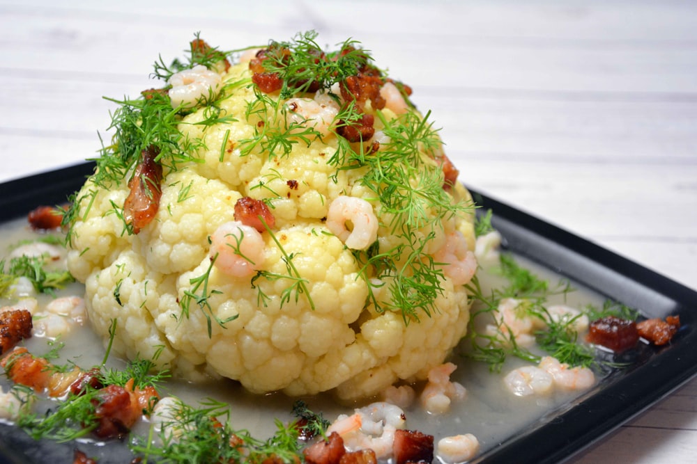 white and green vegetable salad on black plastic tray