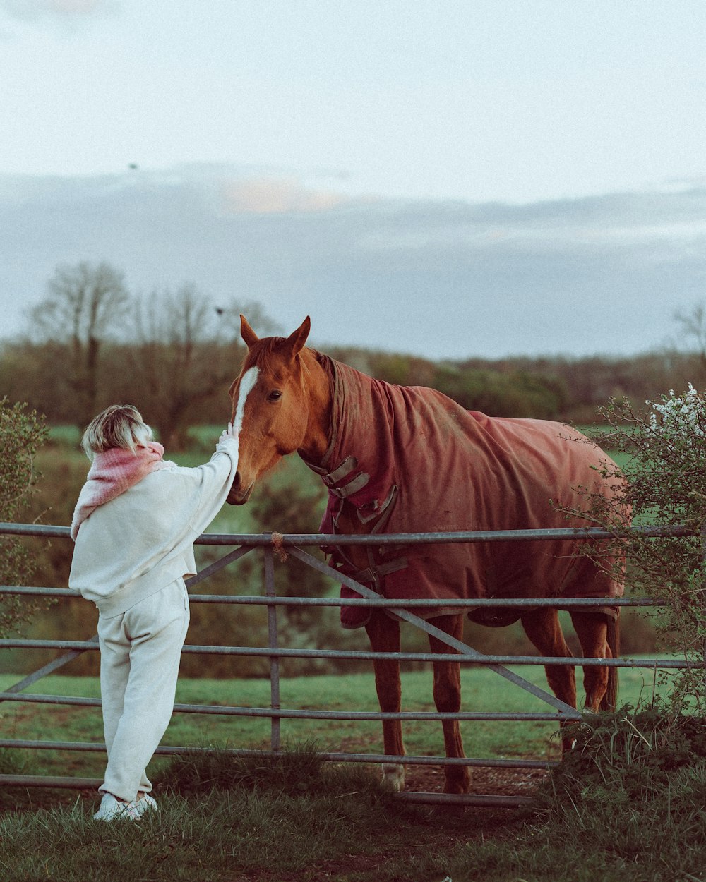 woman in white long sleeve shirt standing beside brown horse during daytime
