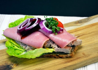 ham sandwich with lettuce and tomato on brown wooden chopping board