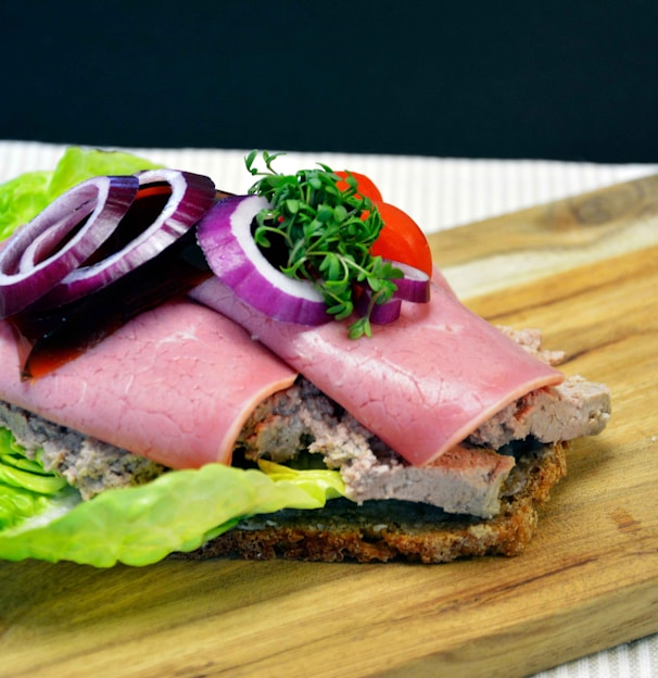 ham sandwich with lettuce and tomato on brown wooden chopping board