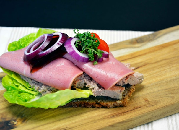 ham sandwich with lettuce and tomato on brown wooden chopping board