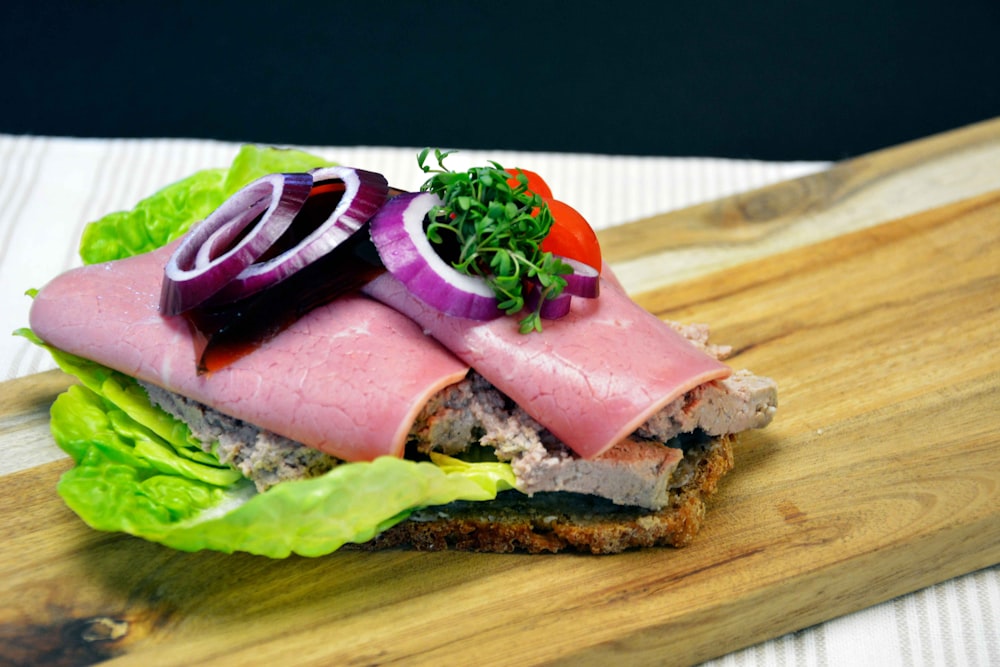 ham sandwich with lettuce and tomato on brown wooden chopping board