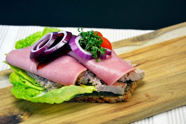 Ham sandwich with lettuce and tomato on brown wooden chopping board
