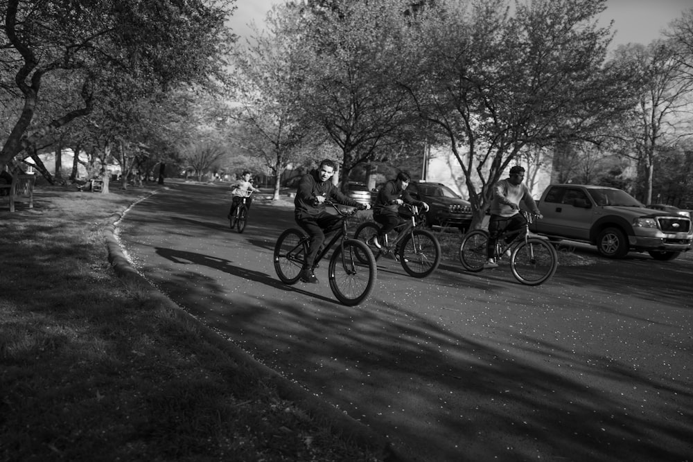 grayscale photo of people riding bicycles on road