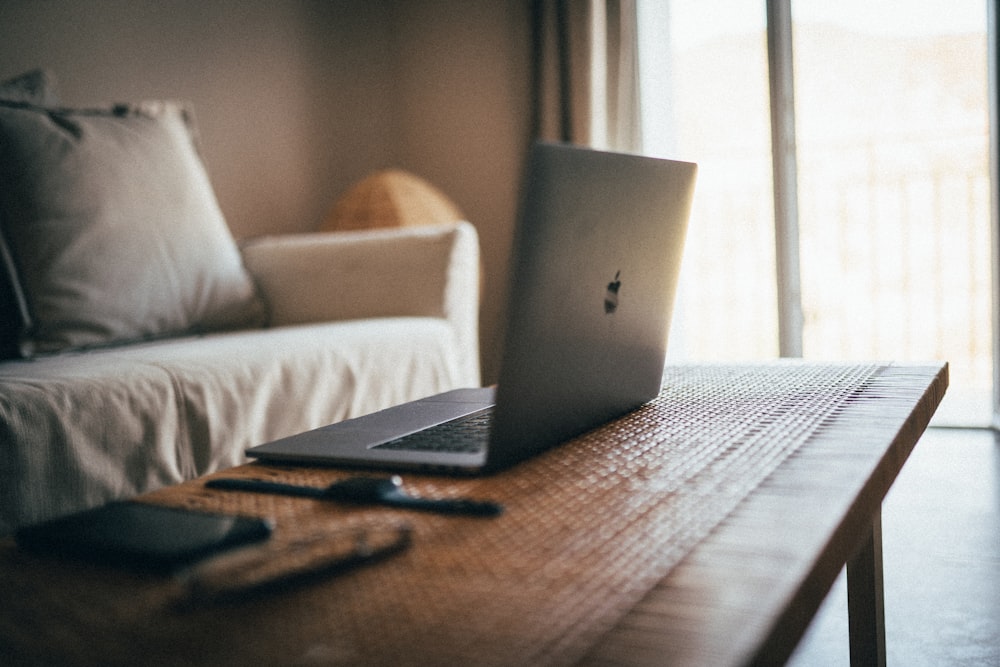 MacBook plateado sobre mesa marrón