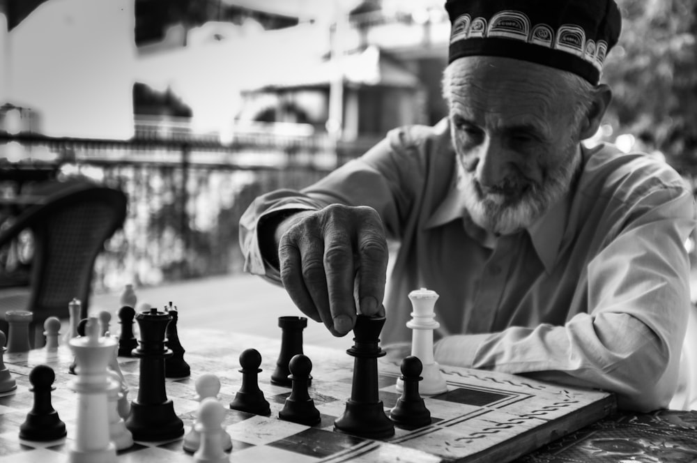 uomo in camicia grigia a maniche lunghe che gioca a scacchi