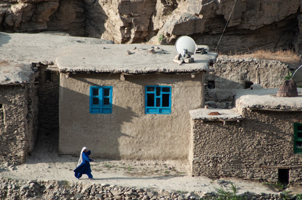 woman in blue dress sitting on gray concrete wall during daytime