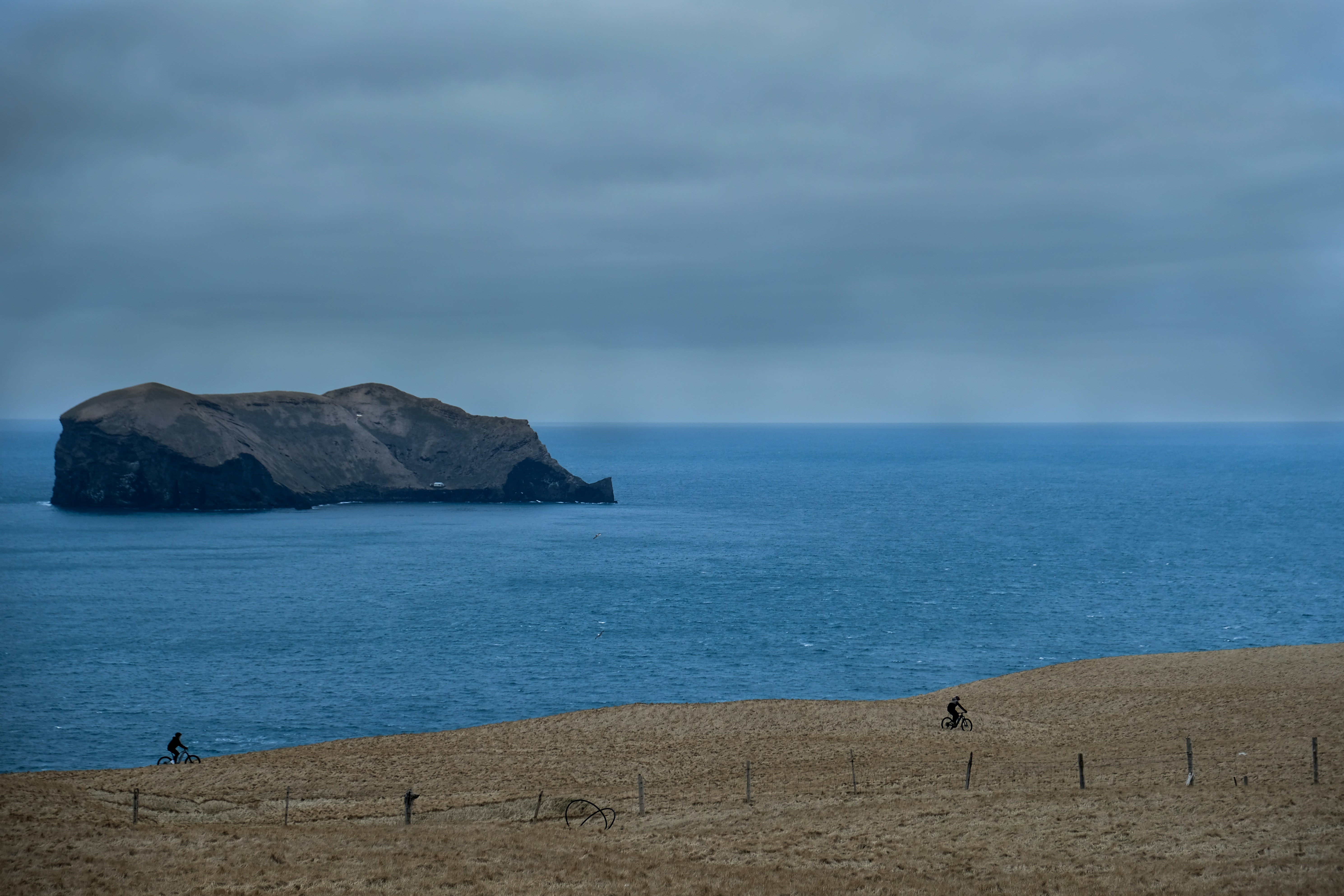 Bikers on a trail, with a sea and island landscape on the background