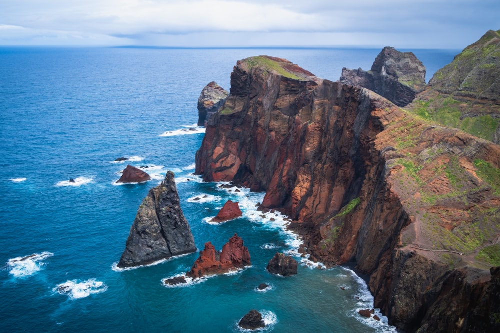 brown and green rock formation on sea during daytime