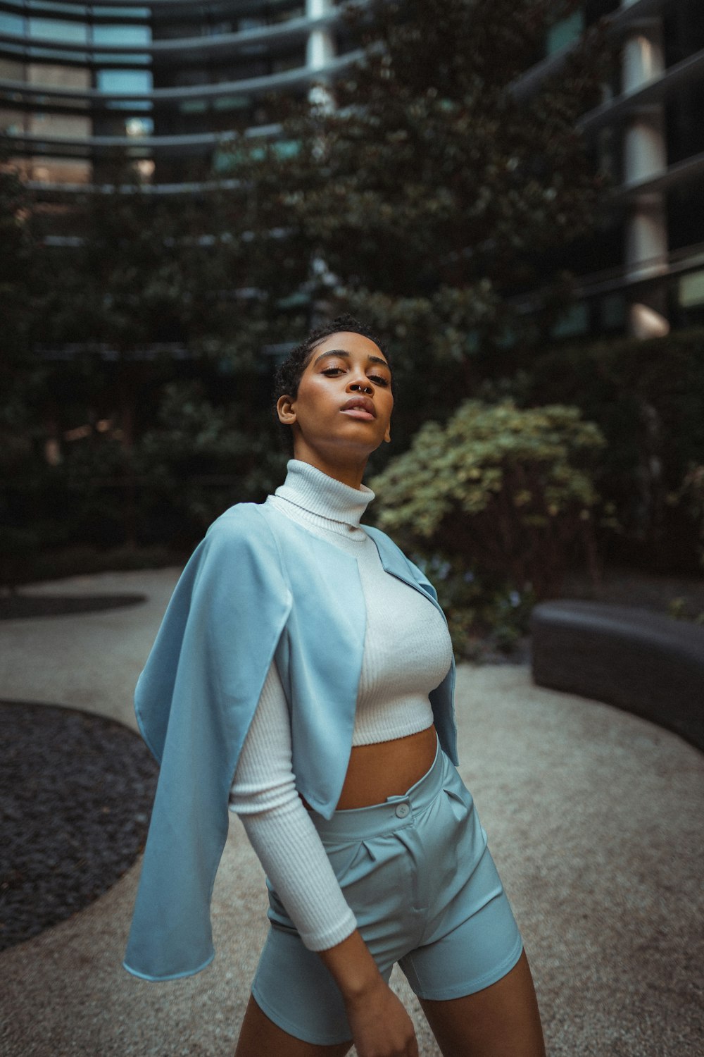 woman in white turtleneck sweater and white cardigan standing on gray concrete road during daytime