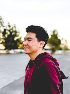 A student wearing a comfortable hoodie and backpack, smiling while walking on campus.