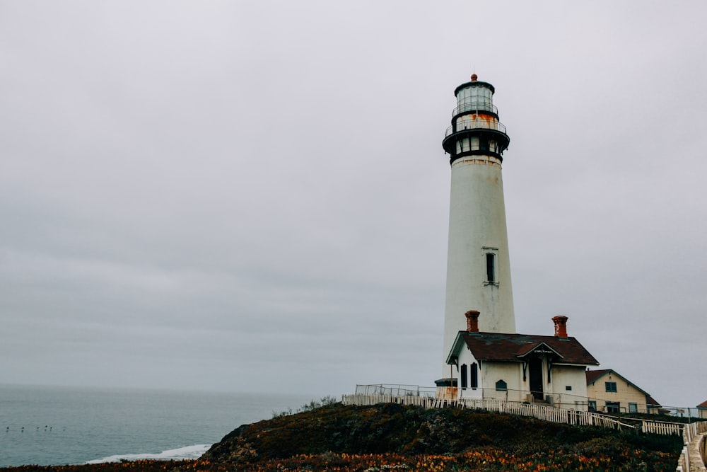 white and red lighthouse on hill under cloudy sky during daytime