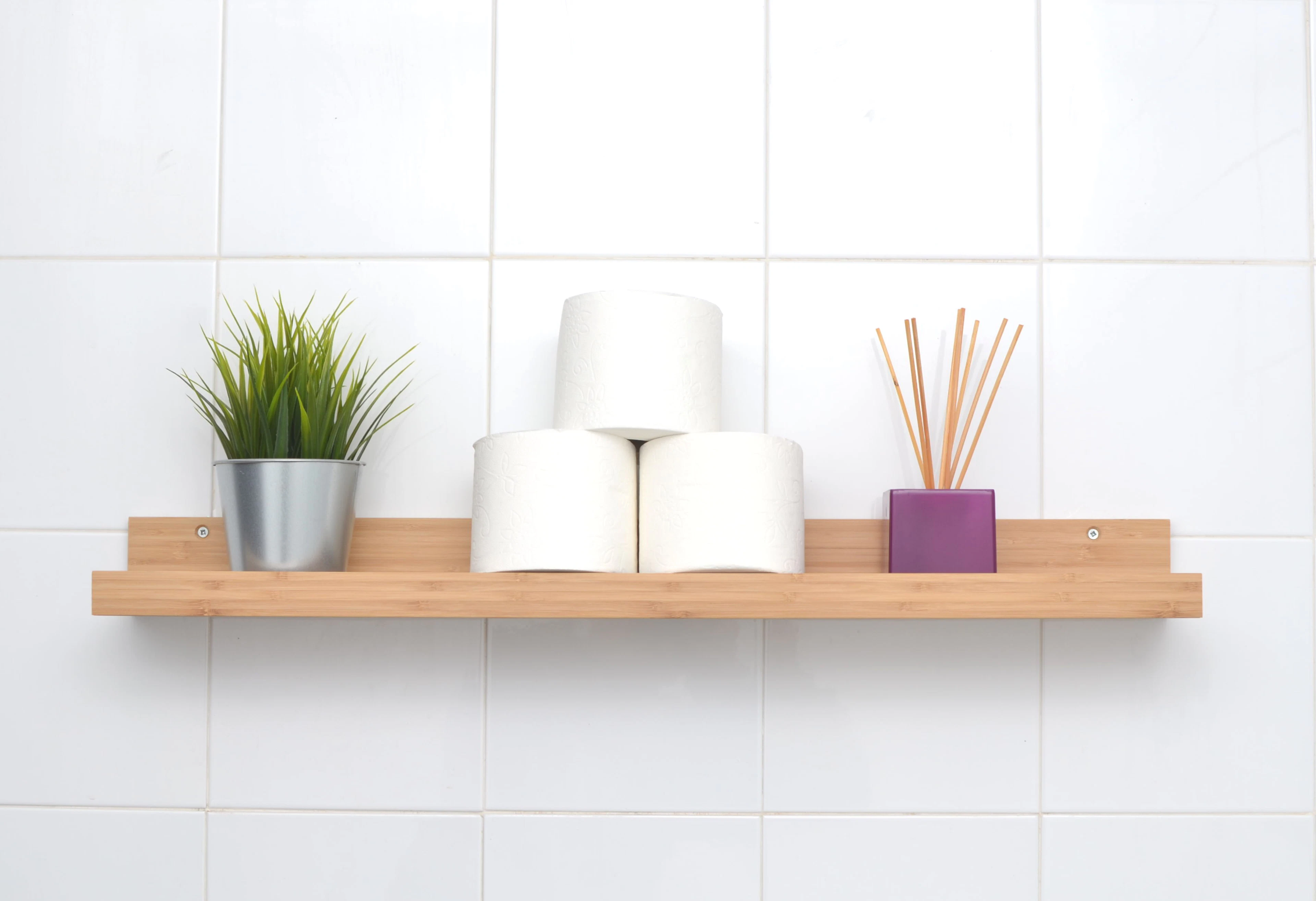 Toilet rolls stacked on a timber shelf against white tiles