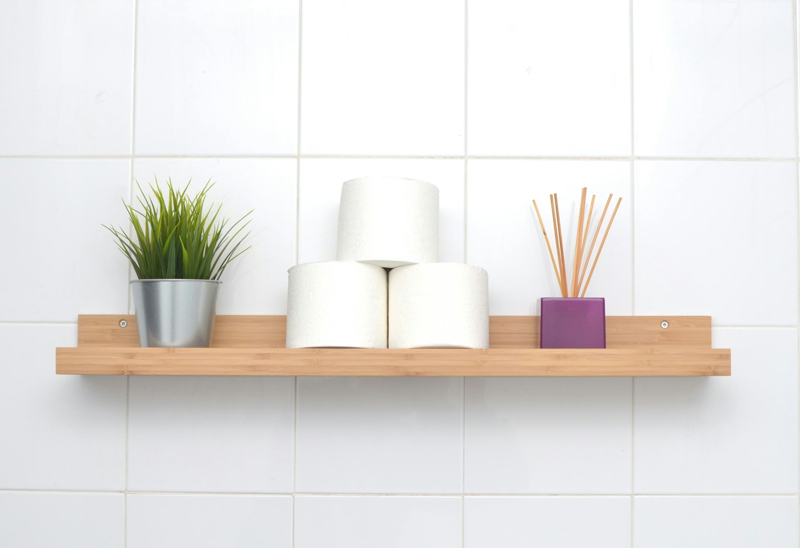 bamboo bathroom shelf with rolled toilet paper plant and reed diffuser