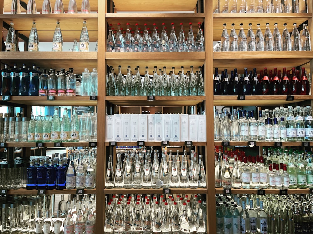 clear glass bottles on brown wooden shelf