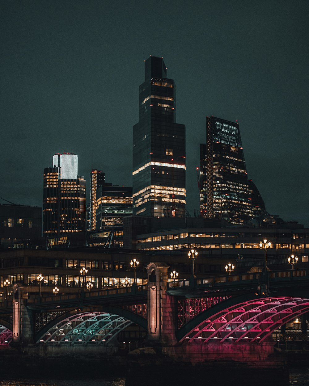 lighted bridge over city skyline during night time