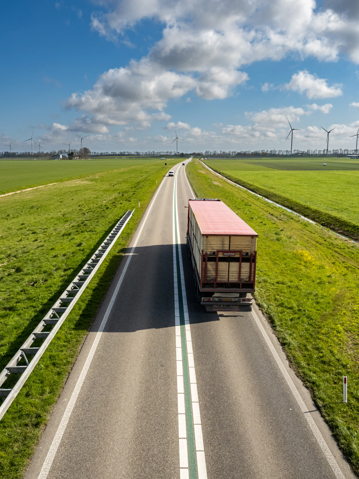 Camion sur une route de campagne en Europe, éoliennes en arrière-plan