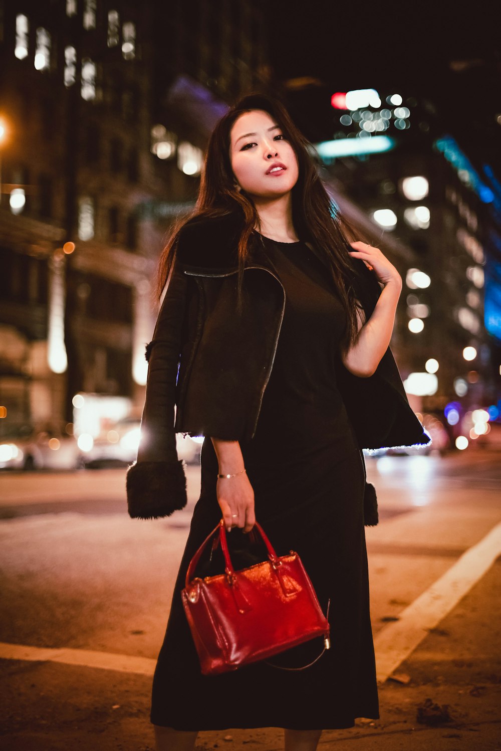 woman in black leather jacket holding red tote bag