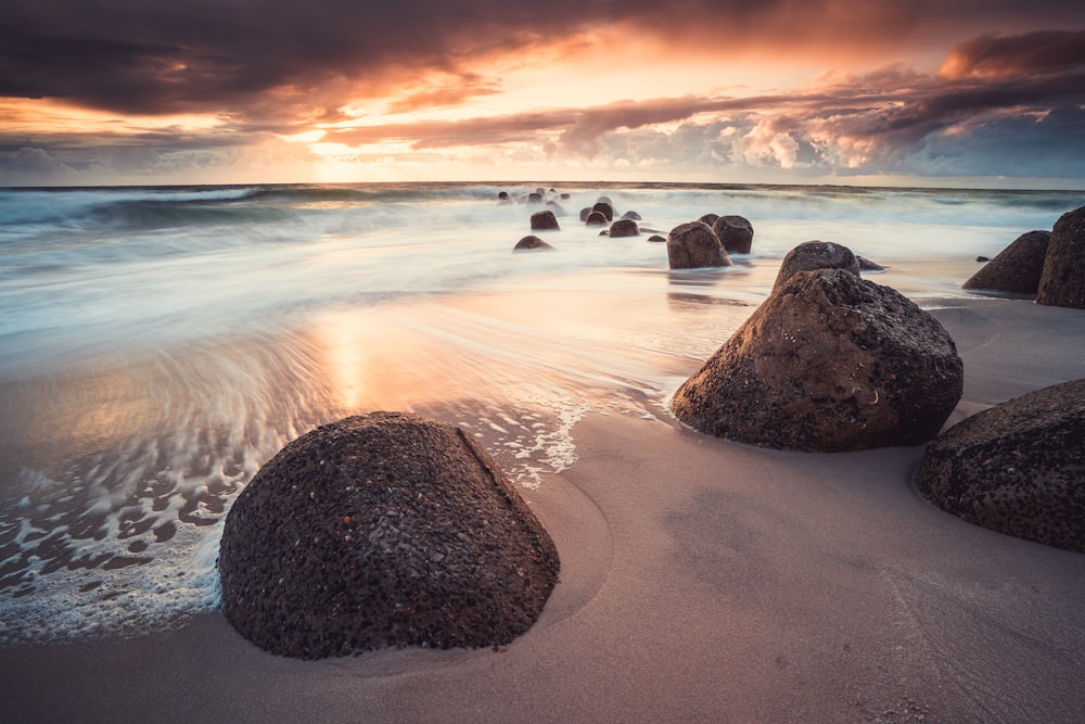 brown rock on seashore during sunset