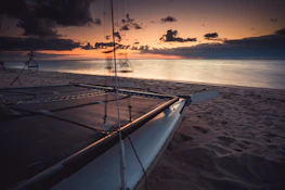 Sunset view over the Caribbean Sea with a silhouette of a catamaran in the distance.