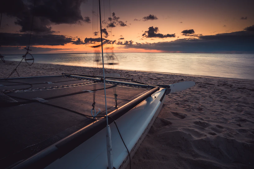 A vibrant sunset over the turquoise waters of Mauritius with a catamaran sailing in the distance.